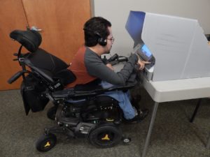 Bill Crowley in his wheelchair using an accessible voting machine